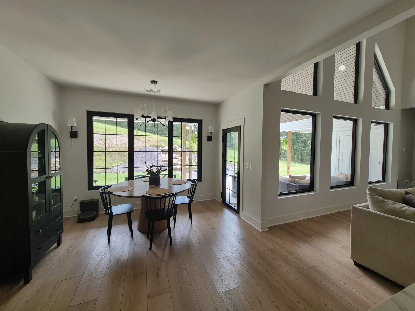 Lived-in dining room with banks of black-framed windows looking onto the yard.