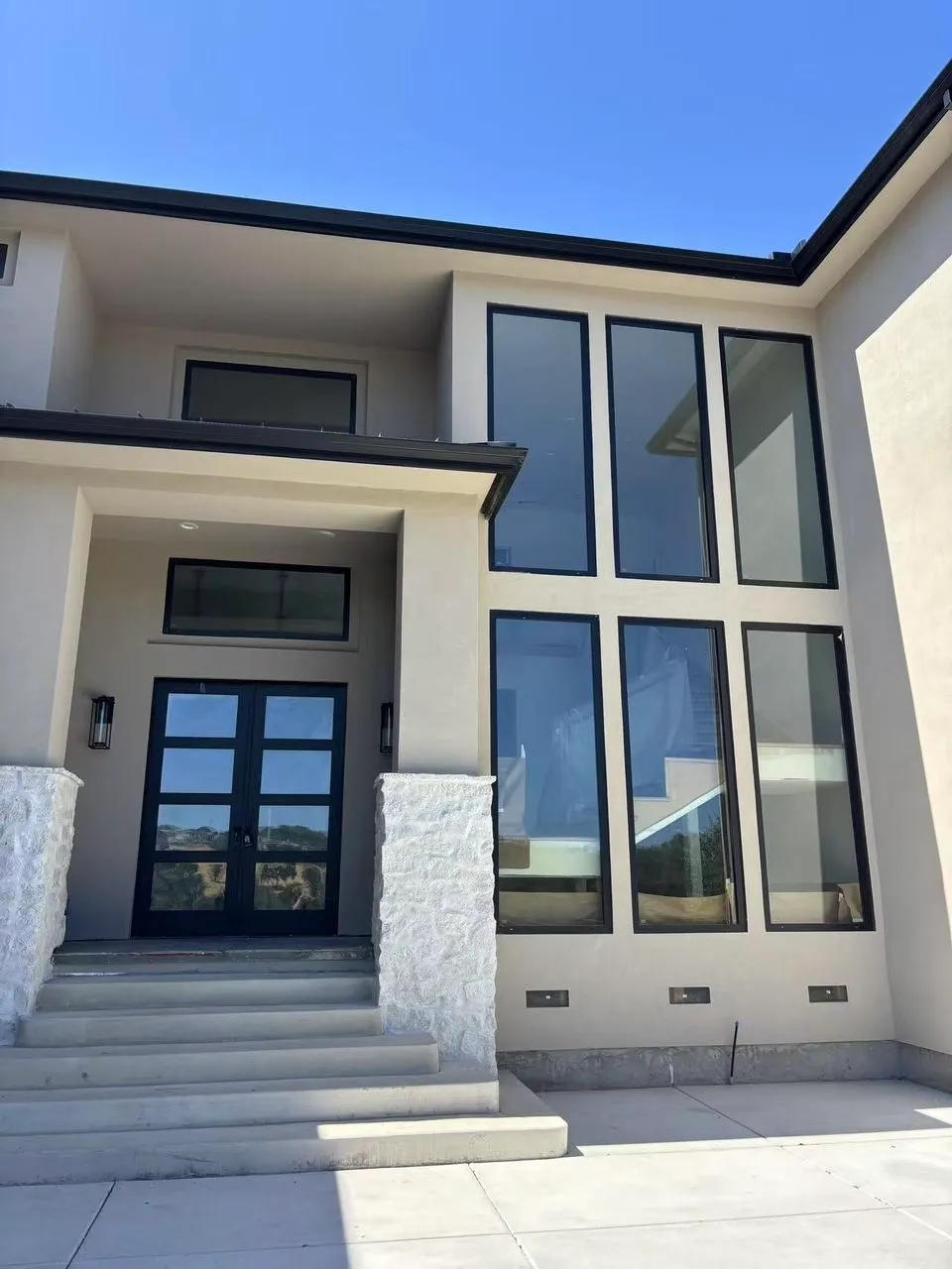 Close-up of a statement pivot entry door in matte black aluminum