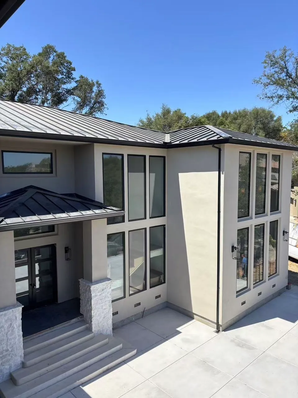 Two-story modern stucco home with tall vertical window banks.