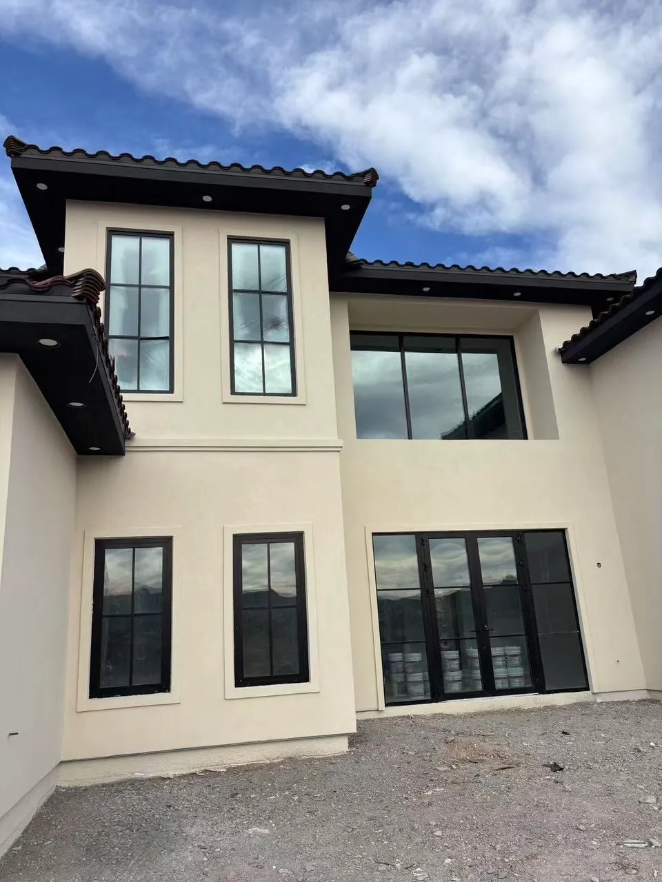 Spanish-style stucco home with black-framed casement and patio doors.