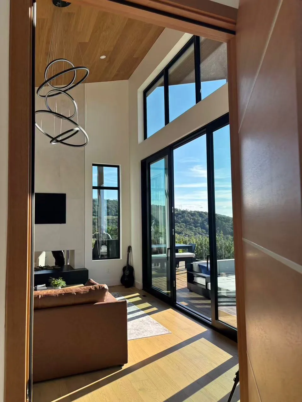Floor-to-ceiling glass framing a mountain view from a luxury hillside living room.